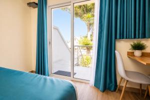 a bedroom with a bed and a window with blue curtains at Aparthotel Madeleine in Antananarivo