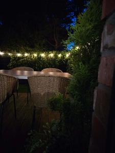 a patio with tables and chairs at night with lights at Apartament Przystań in Łeba