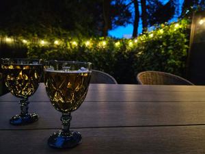 two wine glasses on a wooden table with lights at Apartament Przystań in Łeba