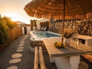 a pool with an umbrella and a table with a bowl of fruit at Casa do tio Frade in Aldeia do Mato