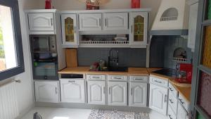 a kitchen with white cabinets and a sink at Belle maison proche du futuroscope in Thuré