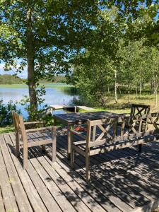 a picnic table and two benches on a deck near a lake at Tamminiemi in Luodonmaa