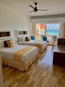 two beds in a hotel room with a view of the ocean at Ventanas al Paraiso Apartment Cancun in Cancún +58 photos