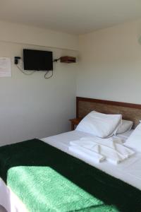 a bedroom with a bed with a green blanket on it at Summit Capitólio Hotel in Capitólio