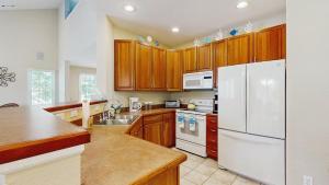 a kitchen with wooden cabinets and a white refrigerator at Bear Trap Dunes - 45D Willow Oak Ave in Ocean View