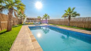 a swimming pool with a fence and palm trees at Belek Glamping House in Çakıllık