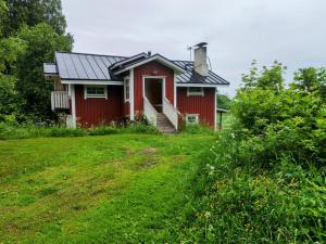 a red house with a porch and a grass yard at Villa Tuomiranta in Porvoo