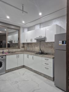 a kitchen with white cabinets and stainless steel appliances at Calm and facinating vacation in Saïdia