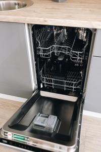an open dishwasher with a cell phone in it at LK Darzu Apartment in Rēzekne