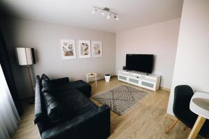 a living room with a black couch and a television at LK Darzu Apartment in Rēzekne