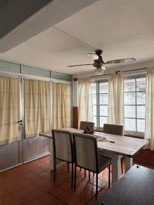 a dining room with a table and chairs and windows at La Casa del Barrio in Ramallo