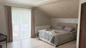 a bedroom with a bed and a large window at ЛІДІЯ in Yasinya