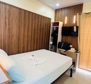 a bedroom with a white bed and a wooden wall at Hotel Costa del Sol in Puerto Limón