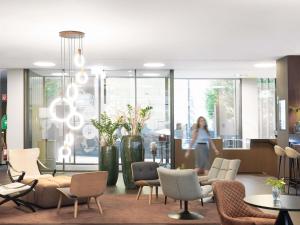 a woman walking through a lobby with chairs and tables at Novotel Lugano Paradiso in Lugano +202 photos