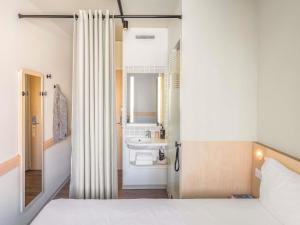 a bedroom with a bed and a bathroom with a sink at ibis budget Lugano Paradiso in Lugano