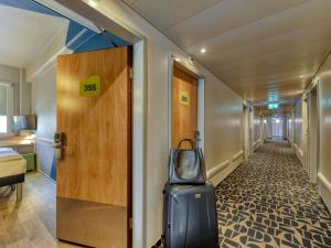 a hallway with a door and a suitcase at ibis budget Hotel Luzern City in Lucerne