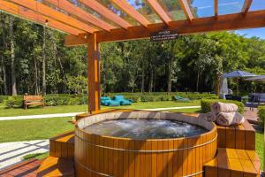 a large hot tub sitting under a wooden pergola at Pousada Cachoeira da Barra in Cunha