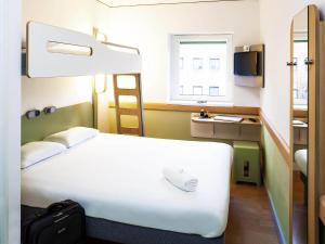 a hotel room with a bed and a ladder and a window at ibis budget Belfast City Centre in Belfast