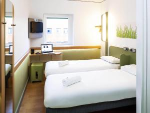 a hotel room with two beds and a laptop on a desk at ibis budget Belfast City Centre in Belfast +66 photos