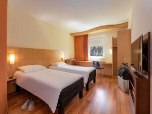a hotel room with two beds and a flat screen tv at ibis Stuttgart Airport Messe in Leinfelden-Echterdingen