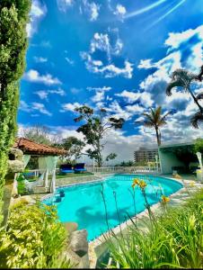 a swimming pool with a blue sky and palm trees at The Butterfly Mansion in Envigado