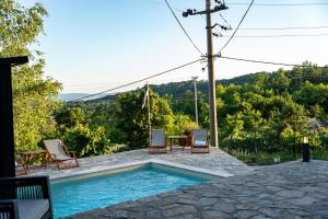 a swimming pool with two chairs and a table at Kosmaj Apartmani Košutica - Marija i Ksenija in Koraćica