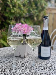 two glasses of white wine on a table with a bottle of wine at Rampestreken Glamping in Åndalsnes
