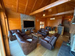 a living room with leather furniture and a flat screen tv at Violetta Cottage in Užice