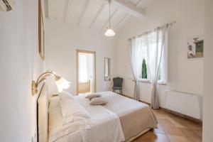 a white bedroom with a bed and a window at La Casa delle Farfalle in Chiusi