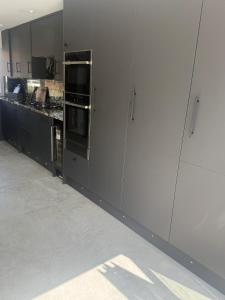 a kitchen with black cabinets and a white wall at The Hideaway Aylesbury in Buckinghamshire +3 photos