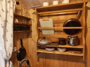 a kitchen with wooden walls and shelves with pots and pans at Villa Tuomiranta in Porvoo