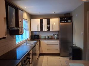 a kitchen with white cabinets and a stainless steel refrigerator at 56 Woodlands in Clonakilty