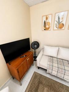 a living room with a couch and a flat screen tv at Vila Chacrinha apartamento 2 in Campo Limpo