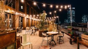 a rooftop patio with tables and chairs and lights at Ruby Louise Hotel Frankfurt by IHG in Frankfurt