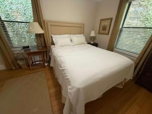 a bedroom with a large white bed and two windows at Stone Cottage 1973 in Lake Junaluska