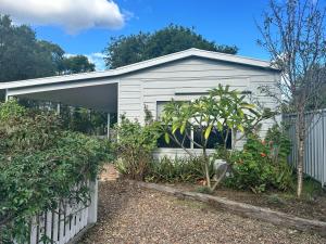 a white house with a fence and some plants at The Hunter Studio in Cessnock