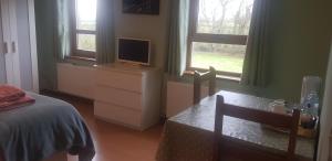 a bedroom with a bed and a desk with a television at Maghernahar House B&B in Ballycastle