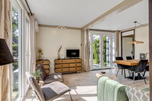 a living room with a table and chairs and a desk at Vrijstaande bungalow met grote privé tuin dichtbij Veerse meer in Kortgene