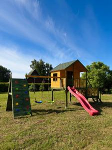 a playground with a slide and a house at Tomaszówka in Sarbinowo