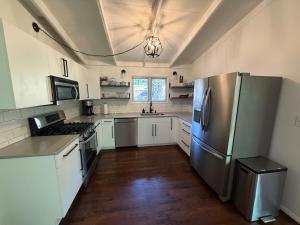 a kitchen with a stainless steel refrigerator and white cabinets at Manville Heights Modern in Iowa City