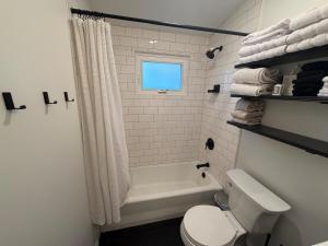 a bathroom with a toilet and a tub and a window at Manville Heights Modern in Iowa City +35 photos