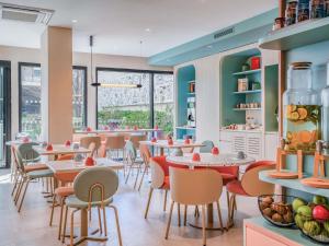 a restaurant with tables and chairs and windows at ibis Styles Paris Porte d'Orléans in Montrouge