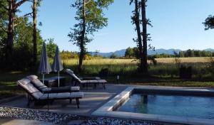 a swimming pool with two chairs and umbrellas next to a pool at Country house Greenfields in Gospić