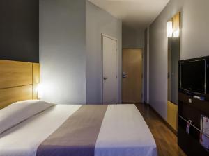 a bedroom with a large bed and a flat screen tv at ibis Jaboticabal in Jabuticabal