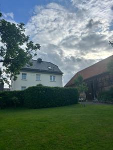 a white house with a hedge in a yard at Huis bij Willingen in Eimelrod