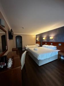 a hotel room with two beds and a desk at Imperial Hotel Galway in Galway