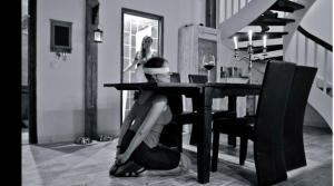 a woman sitting at a table in a dining room at Romantisches SM Apartment Secret Passion in Fehmarn