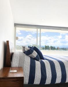 a bedroom with a striped bed with a large window at APARTAMENTO FAMILIAR EN PAIPA RÚSTlCO 70-9 in Paipa