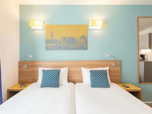 two beds in a room with blue walls at Aparthotel Adagio Access La Défense - Place Charras in Courbevoie