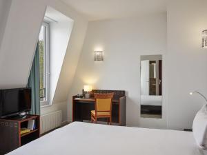 a bedroom with a bed and a desk and a television at Aparthotel Adagio Access Paris Philippe Auguste in Paris